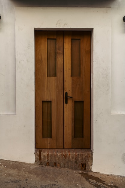 a wooden door on the side of a white building