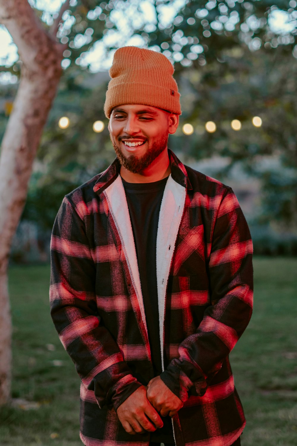 a man with a beard wearing a plaid jacket and a beanie