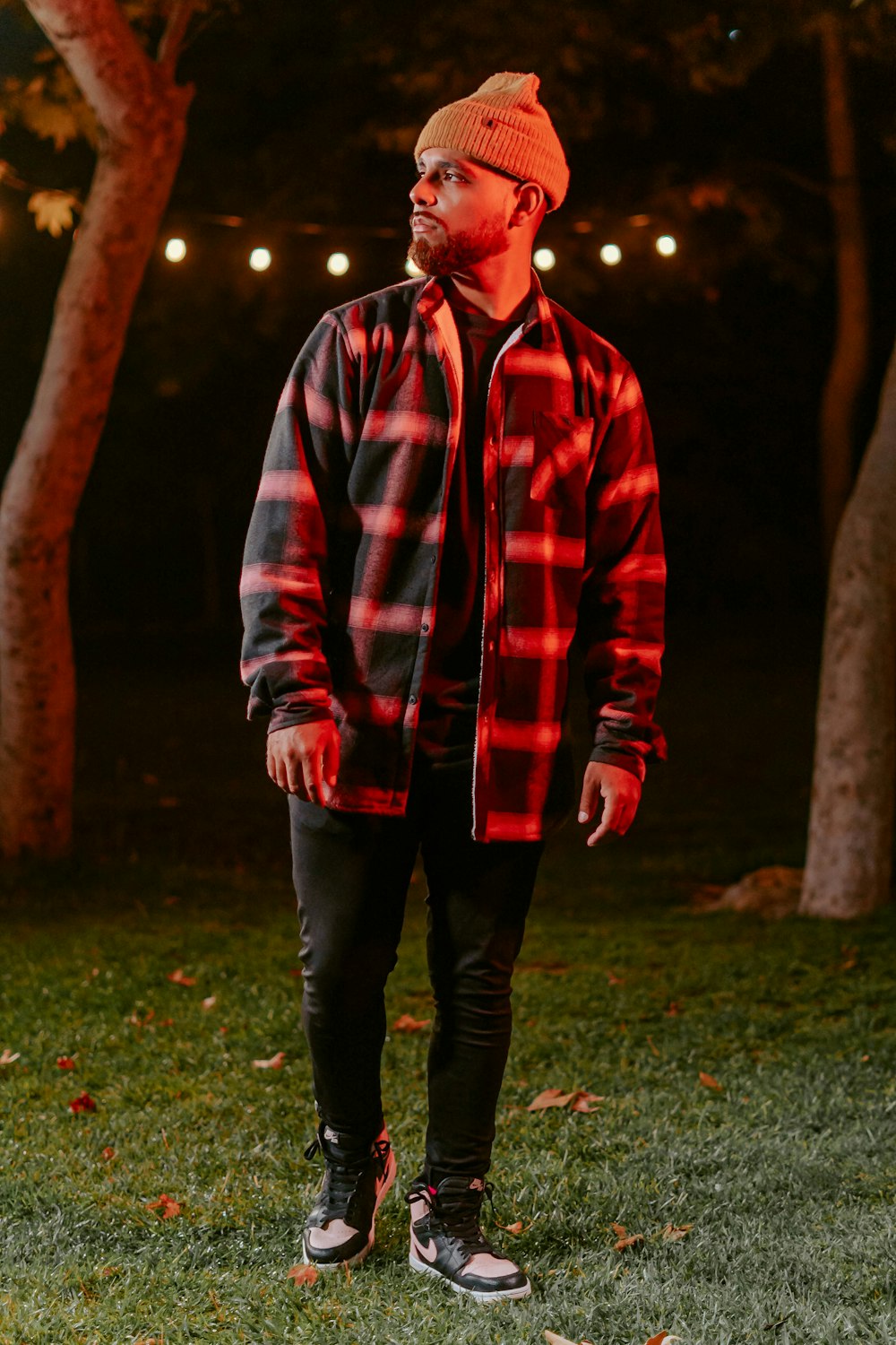 a man standing in the grass wearing a red and black jacket