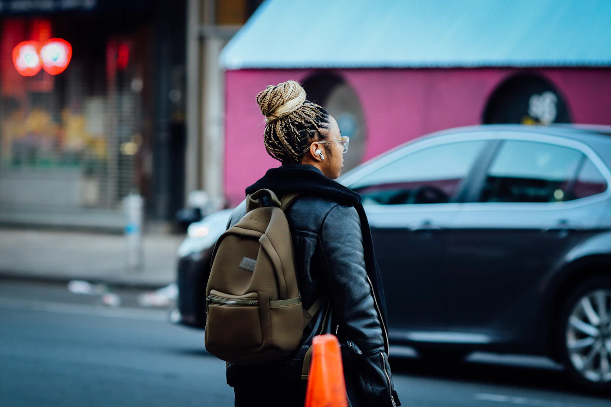 A woman walking alone down a city street carrying a backpack