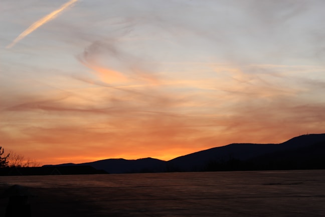 Close-up of a glossy metal print featuring a colorful sunset over mountains.