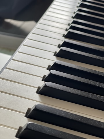 Close-up of hands playing a polished piano keyboard with natural sunlight.
