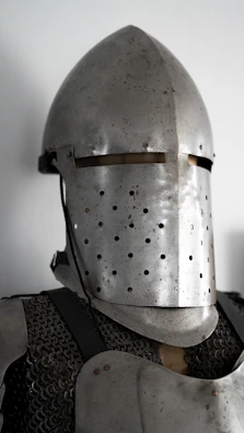 Close-up of a shining medieval helmet and chainmail resting on a wooden table.