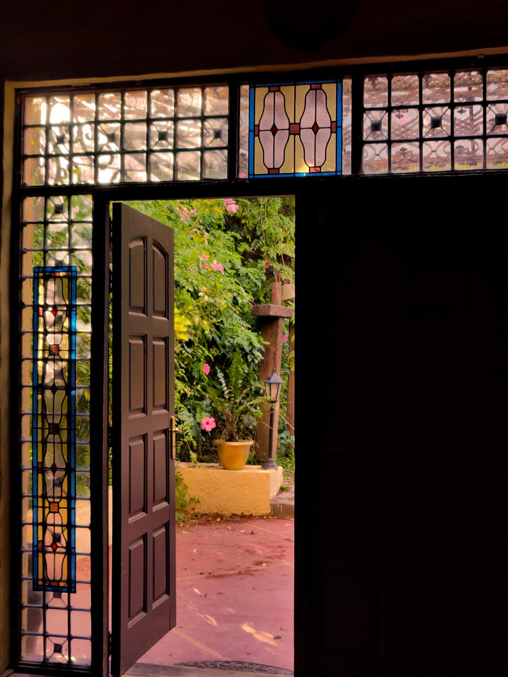 an open door leading to a garden with potted plants