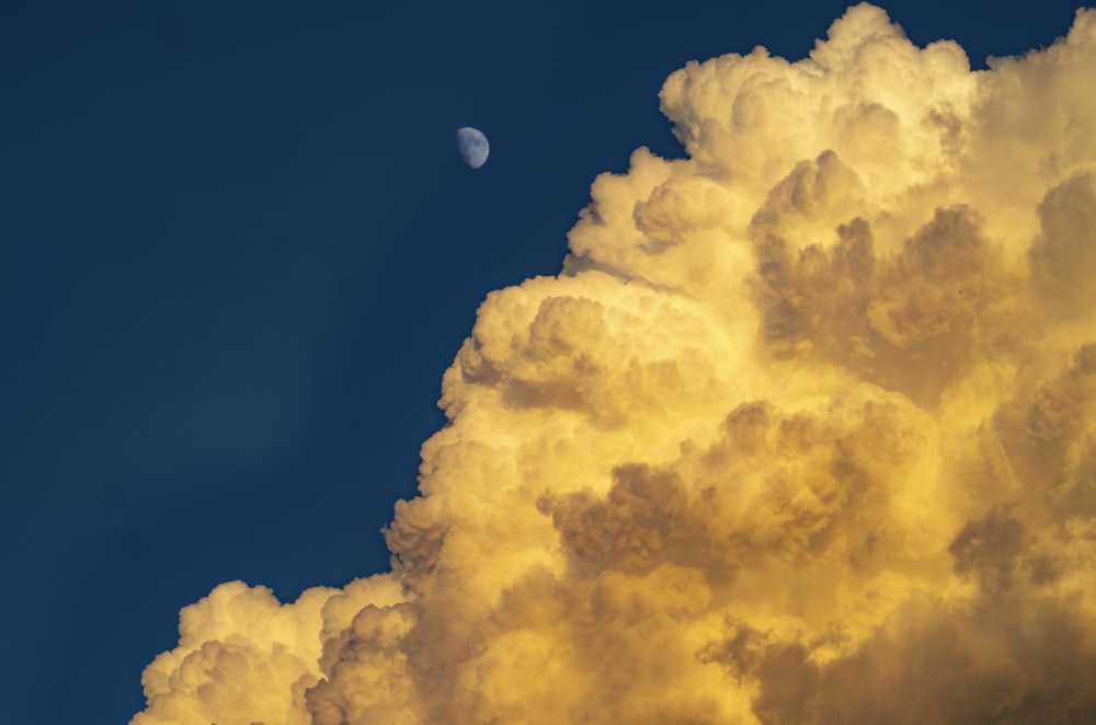 a cloud with a half moon in the distance