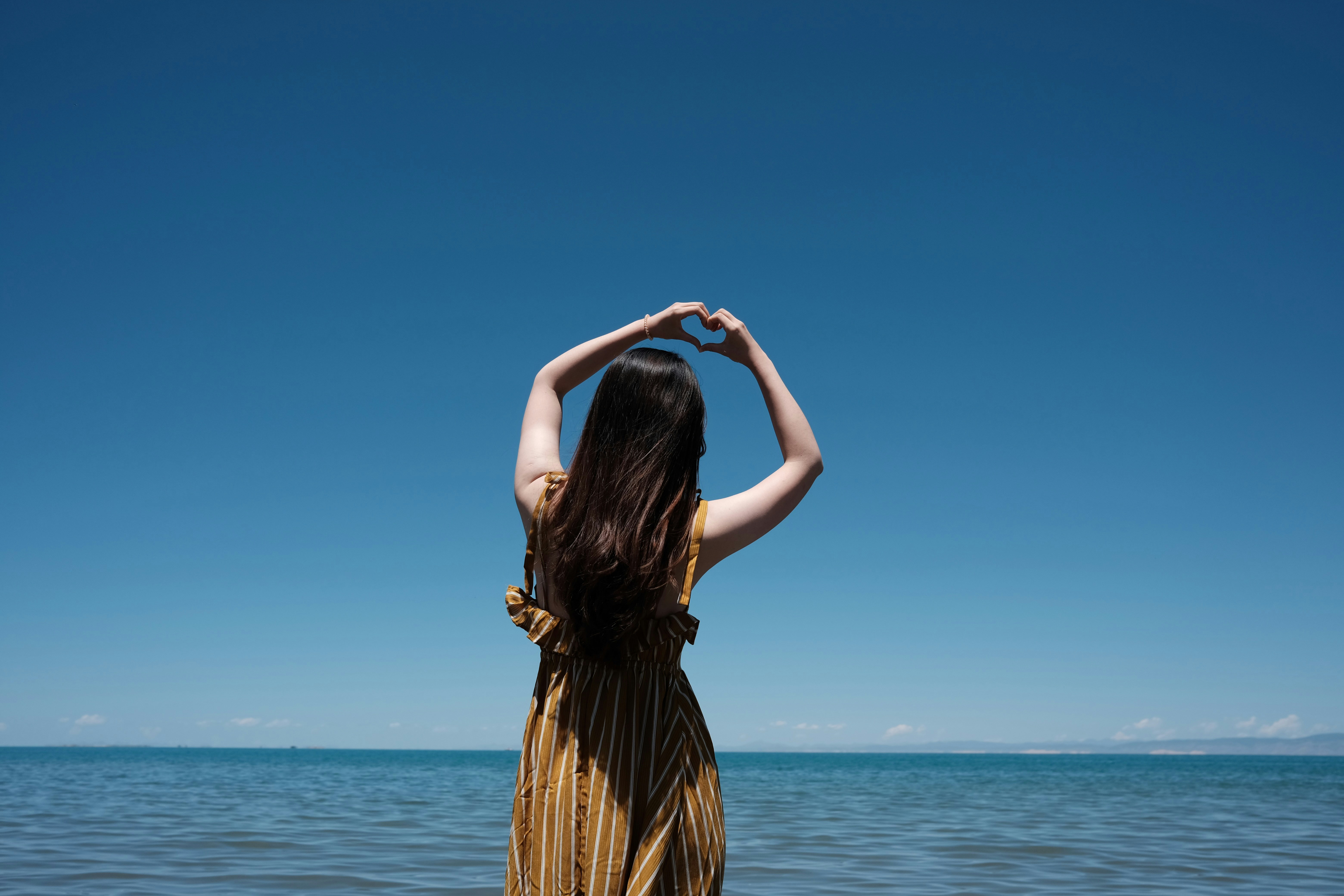 a woman standing on a beach with her hands in her hair