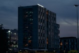 A sleek modern skyscraper at dusk with warm interior lights glowing.