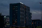 A completed technology-integrated building glowing warmly at dusk, showcasing smart lighting.