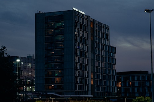 A sleek, modern office tower at dusk with warm interior lights glowing.