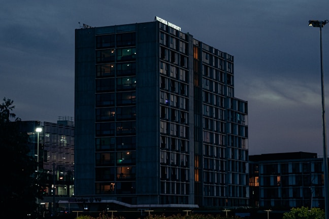 A sleek modern skyscraper at dusk with warm interior lights glowing.