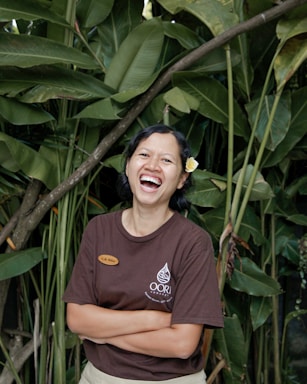 A friendly customer service representative smiling with a headset, surrounded by green plants.