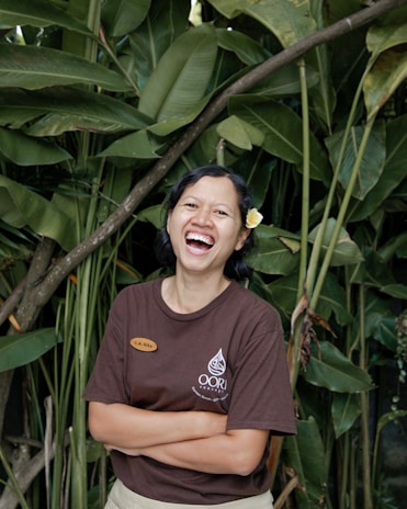 A smiling gardener from 5 starr aina gently pruning tropical plants in a vibrant garden.
