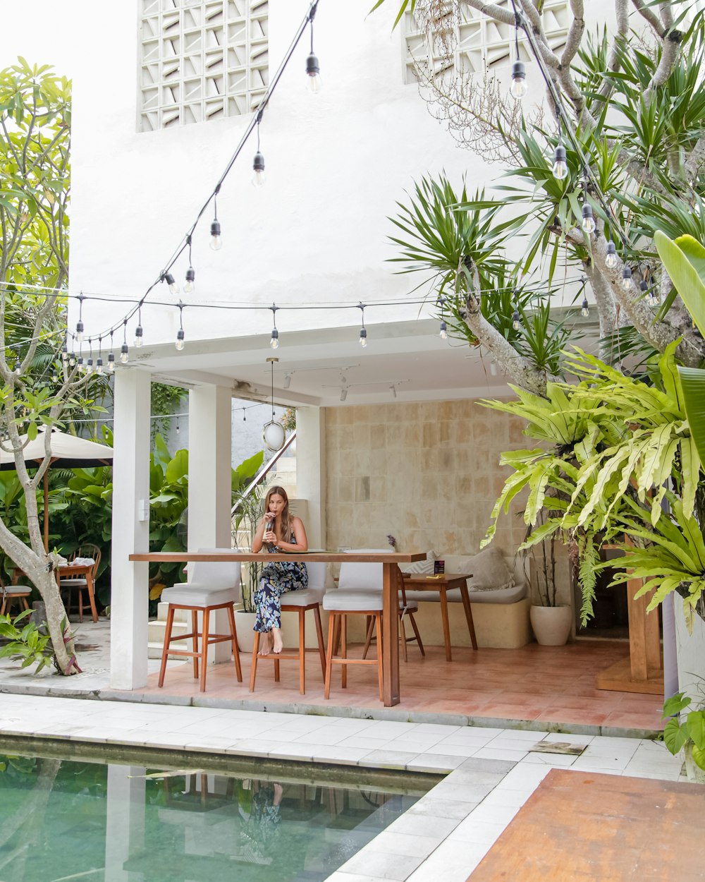 a woman sitting at a table next to a pool