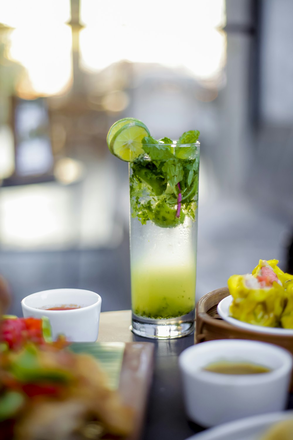 a glass filled with a green drink next to a plate of food