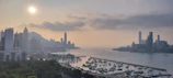 A panoramic view of a bustling Hong Kong skyline at sunset highlighting prime land areas