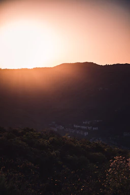 A serene Texas Hill Country sunset behind a luxury estate, casting warm golden light on rolling hills.