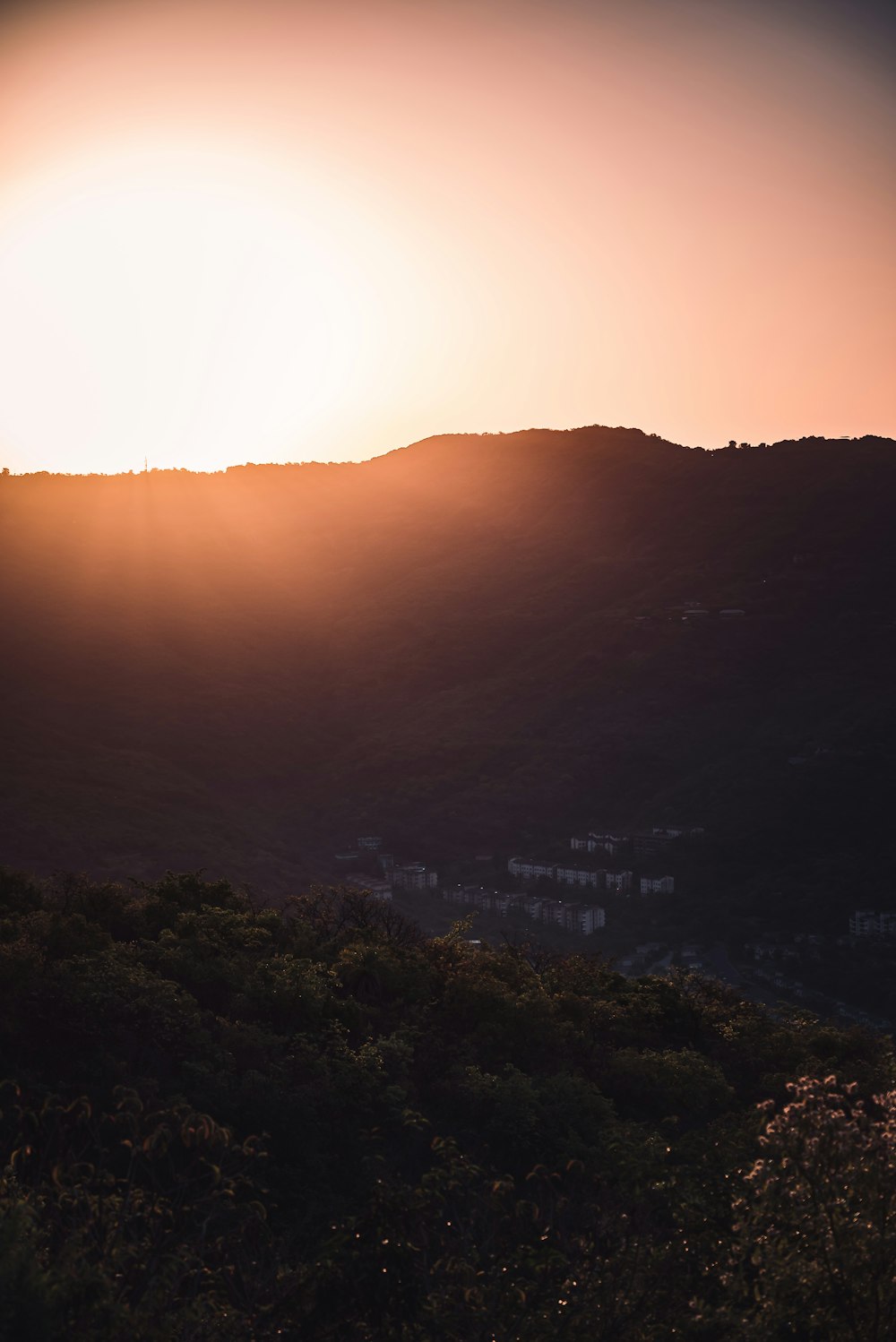 the sun is setting over the hills and trees