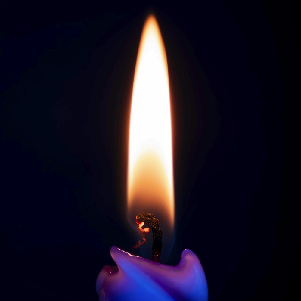 a candle with a blue flame on a black background