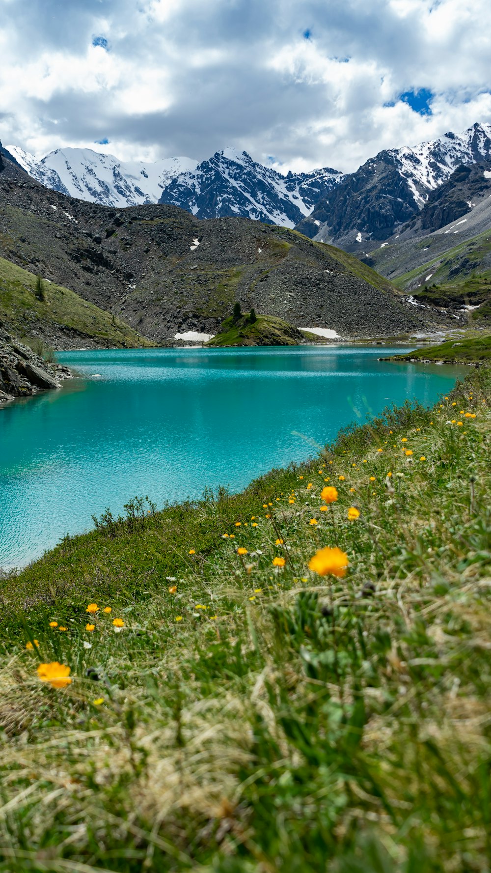 a blue lake surrounded by mountains and grass