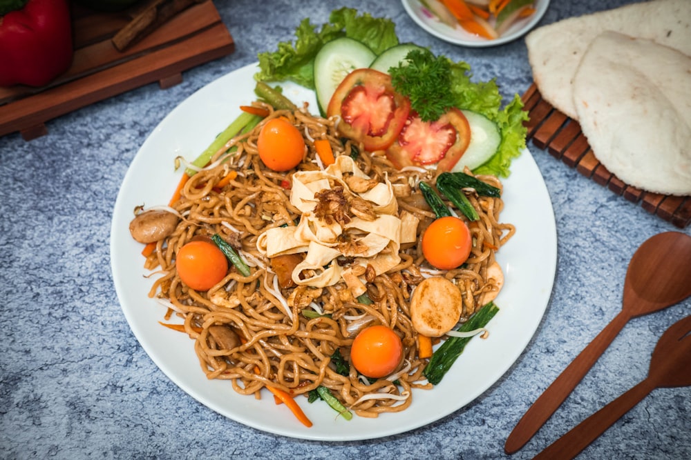 a white plate topped with noodles and veggies