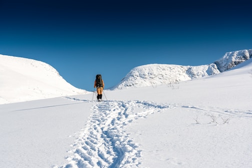 A scenic wide shot of mountainous terrain with a lone hiker in outdoor clothing.