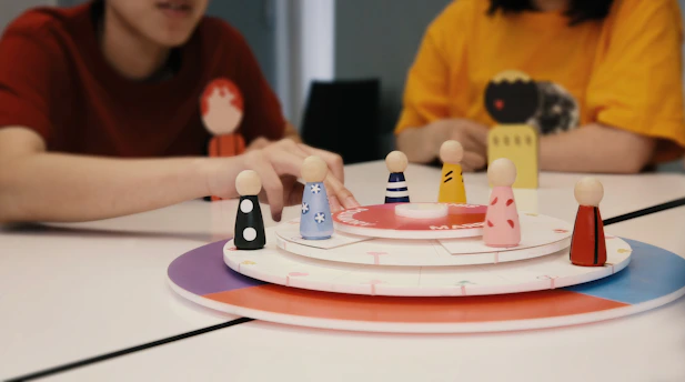 Two people playing a board game with wooden figures.