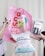 Several hands are holding various gardening and plant care products against a light background. These include a pink banner with bold red text, a bottle of plant spray, gardening tags, bottles of liquid fertilizer, and bags of plant soil labeled in German.