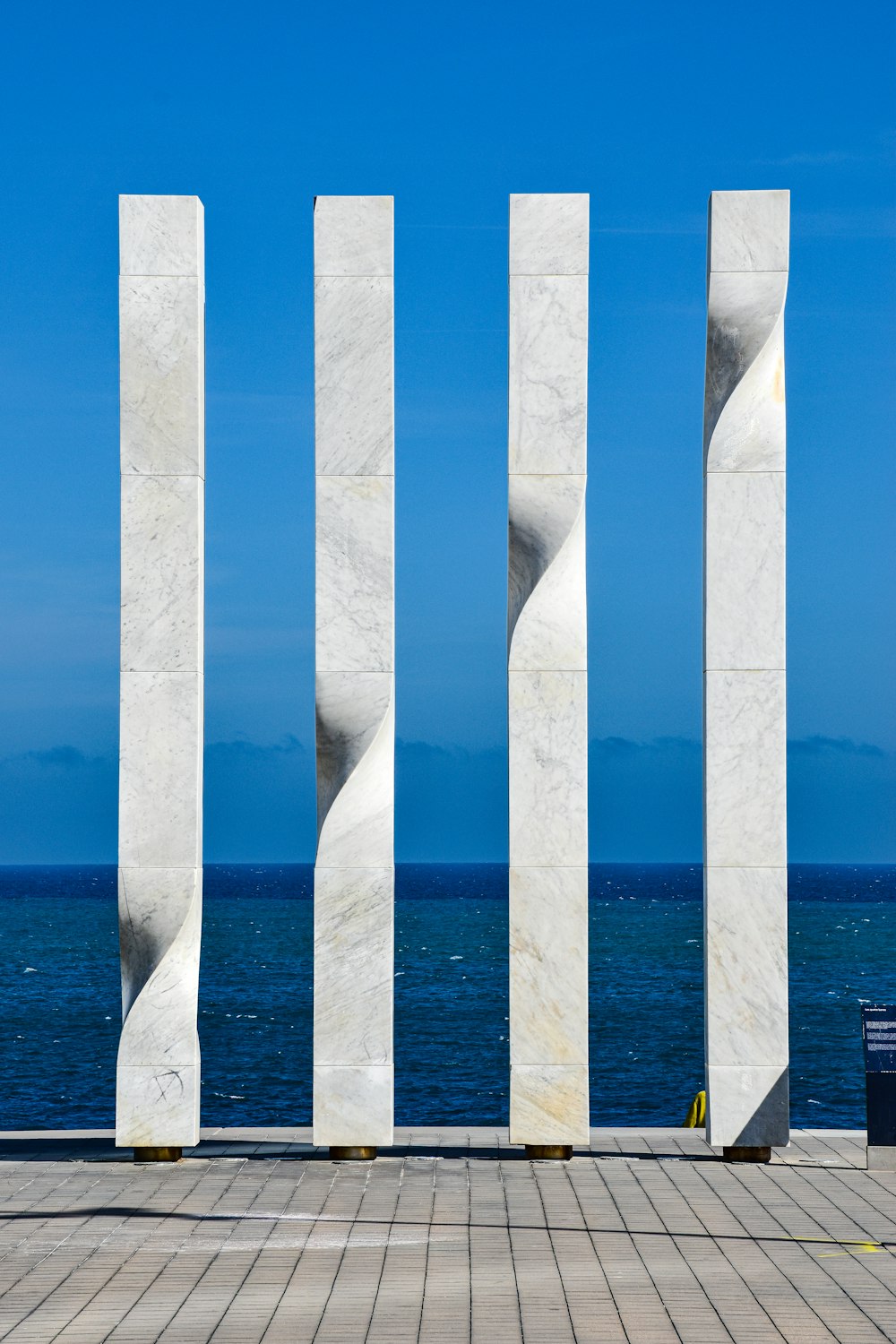a couple of tall white pillars sitting next to the ocean