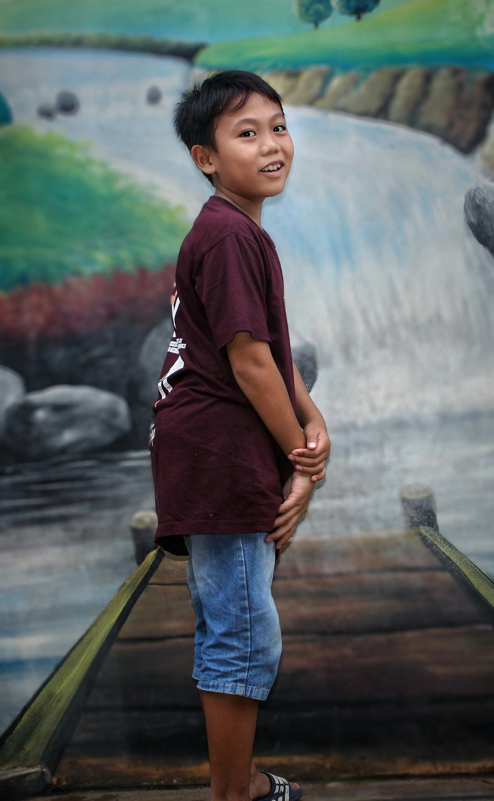a young boy standing in front of a painting