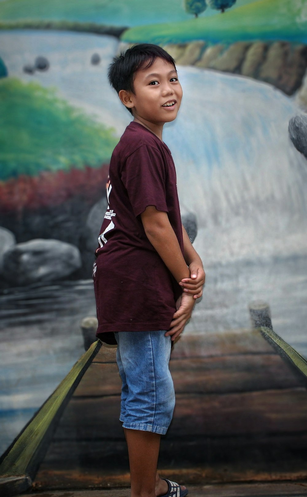 a young boy standing in front of a painting