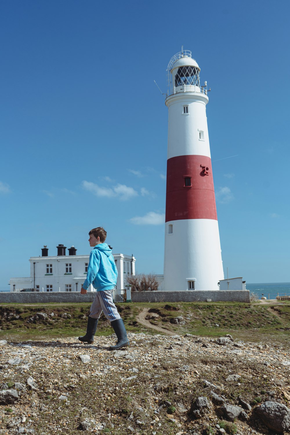 a man walking in front of a red and white lighthouse