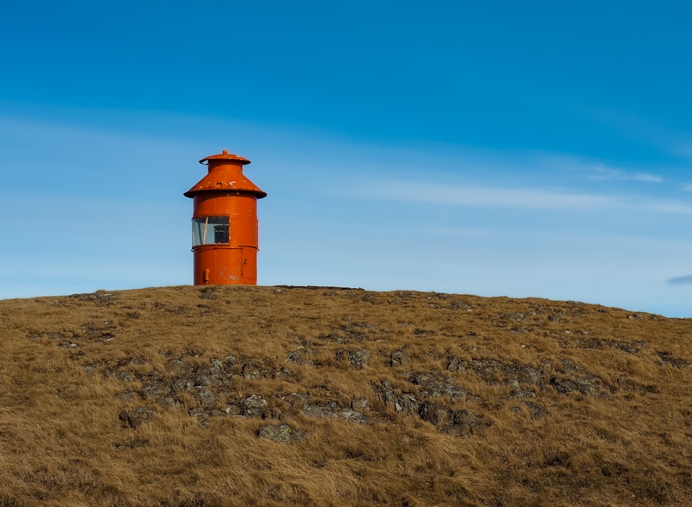 an orange lighthouse on a hill with a blue sky in the background