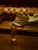 A cozy corner of Evelyn's on Oak with amber lighting and a glass of whiskey on the table.