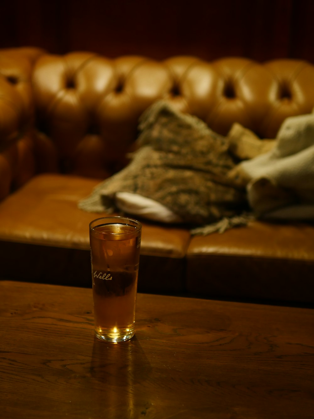 a glass of alcohol sitting on a table next to a couch