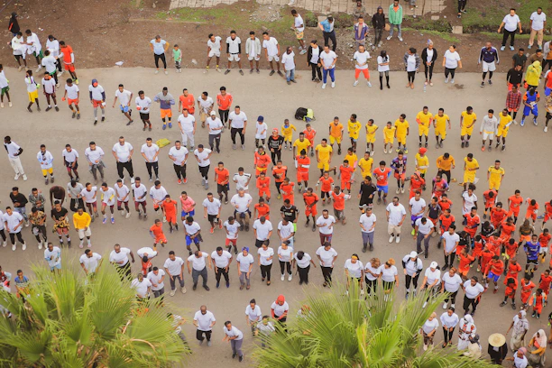 A vibrant group of youth performing an energetic drill routine outdoors under bright sunlight.