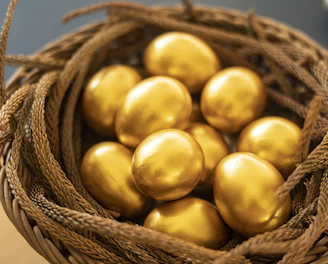 a basket filled with gold colored eggs on top of a table