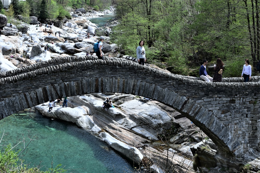 a group of people standing on a stone bridge over a river