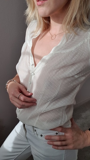 A close-up of a woman wearing a sleek, cream-colored silk blouse with delicate golden accents, embodying quiet luxury.