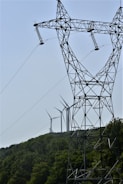 a group of power lines with wind turbines in the background