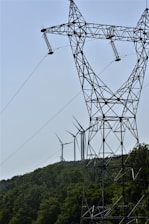 a group of power lines with wind turbines in the background