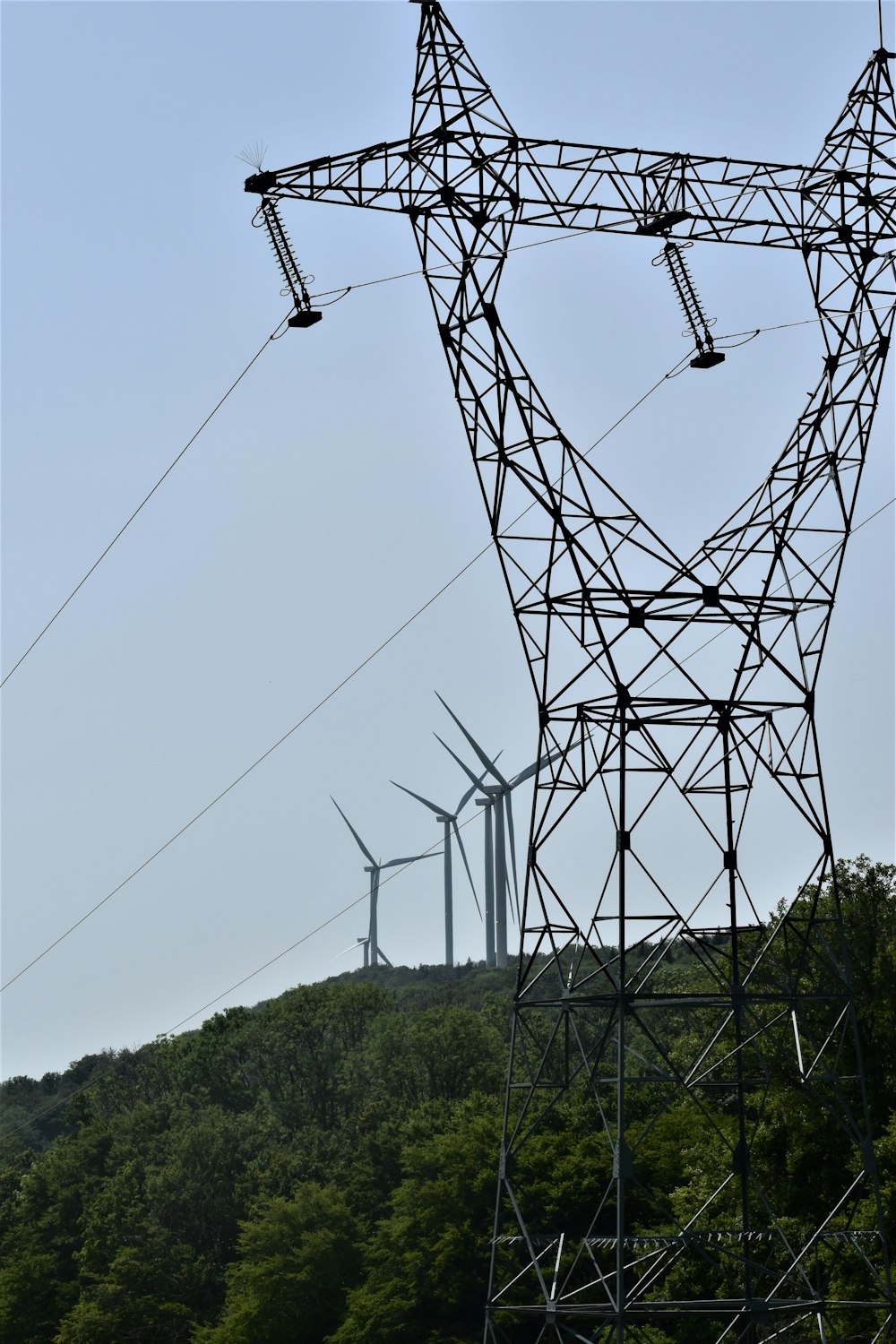a group of power lines with wind turbines in the background