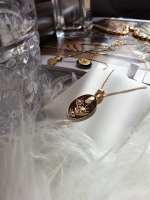 Close-up of a delicate gold necklace with a sparkling diamond pendant resting on a velvet cushion.