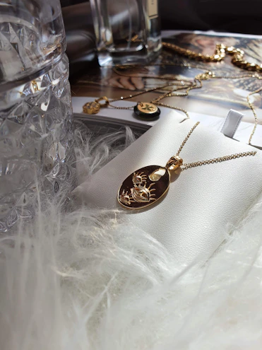 Softly lit close-up of a delicate gold pendant resting on a cream linen cloth.