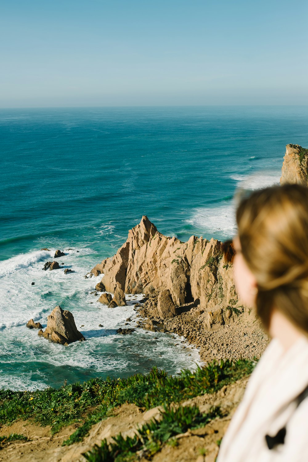 a woman standing on a cliff overlooking the ocean