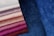 Various shades of fabric are displayed, ranging from pale white and beige to rich purple and deep blue. The fabrics have a velvety texture, capturing light and creating a soft, luxurious appearance.