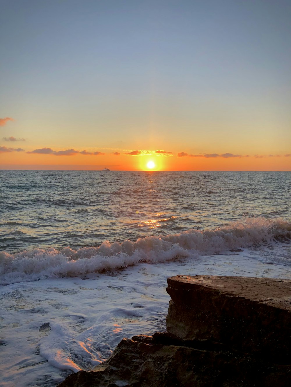 a sunset over the ocean with waves coming in