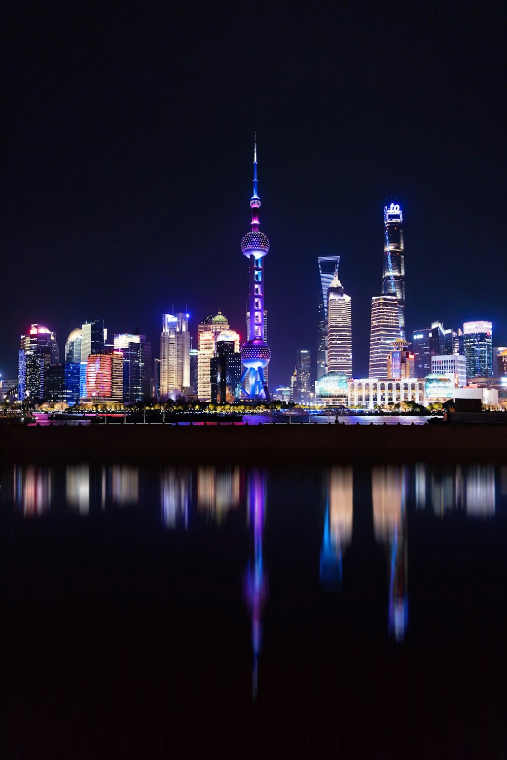 a city skyline at night with a reflection in the water