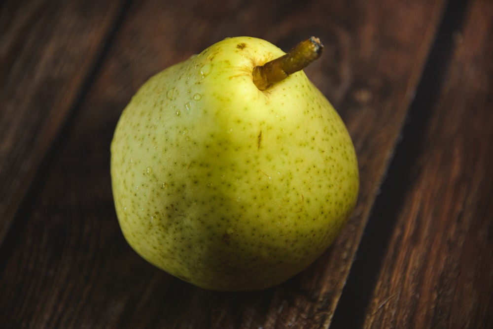 a green apple sitting on top of a wooden table