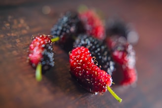 Close-up of fresh mulberries, lemons, and lavender flowers arranged on a wooden table.