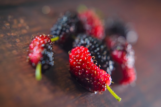 Close-up of fresh mulberries, lemons, and lavender flowers arranged on a wooden table.